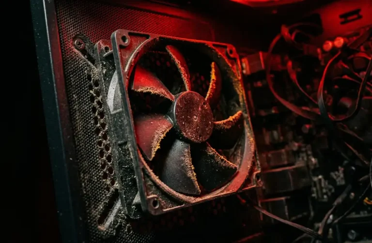 Fan de gabinete de PC coberta de poeira, iluminada em vermelho, ilustrando os riscos de um kit de fans mal escolhido ou mal cuidado